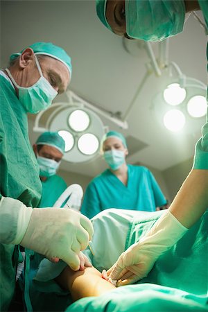 simsearch:400-06734621,k - Team of surgeons using scalpel to open a patient in a surgical room Stock Photo - Budget Royalty-Free & Subscription, Code: 400-06734078