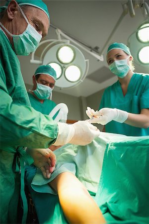simsearch:400-06734621,k - Team of surgeons operating the arm of a patient in a surgical room Stock Photo - Budget Royalty-Free & Subscription, Code: 400-06734079