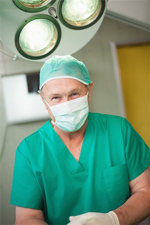 simsearch:400-06734621,k - Surgeon smiles as he stands in a surgical room Stock Photo - Budget Royalty-Free & Subscription, Code: 400-06734089