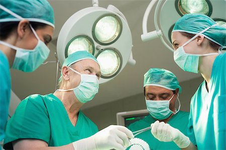 simsearch:400-06734621,k - Surgeon team working together in a surgical room Stock Photo - Budget Royalty-Free & Subscription, Code: 400-06734090