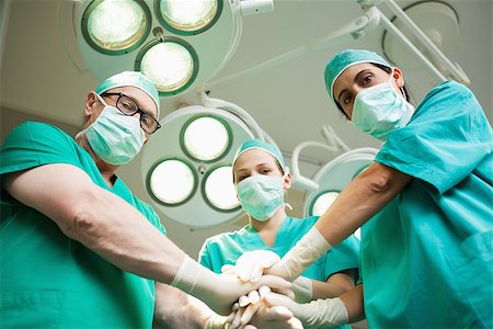 simsearch:400-06734621,k - Surgical team joining hands in a surgical room Stock Photo - Budget Royalty-Free & Subscription, Code: 400-06734101