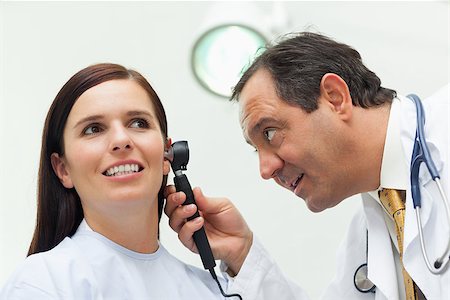 simsearch:400-06734647,k - Doctor using an otoscope to look at the ear of his patient in an examination room Stock Photo - Budget Royalty-Free & Subscription, Code: 400-06734166