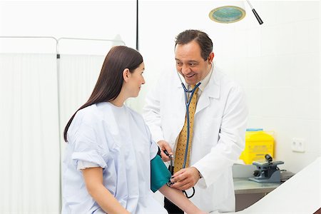 Smiling doctor placing a sphygmomanometer in an examination room Stock Photo - Budget Royalty-Free & Subscription, Code: 400-06734160