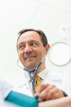 Smiling doctor measuring the blood pressure of his patient in an examination room Stock Photo - Budget Royalty-Free & Subscription, Code: 400-06734163