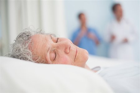 Elderly patient sleeping on a bed next to a doctor in hospital ward Stock Photo - Budget Royalty-Free & Subscription, Code: 400-06734206