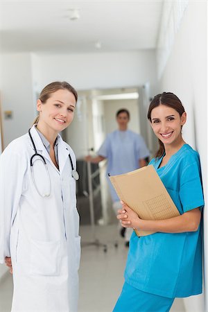 simsearch:400-06875952,k - Doctor and a nurse against a wall standing side by side in a hallway in a hospital Stockbilder - Microstock & Abonnement, Bildnummer: 400-06734246