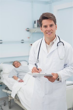 Doctor holding a chart while smiling in hospital ward Stock Photo - Budget Royalty-Free & Subscription, Code: 400-06734376