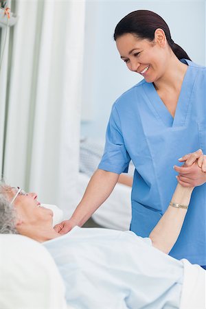 Nurse smiling to a patient while holding her hand in hospital ward Stock Photo - Budget Royalty-Free & Subscription, Code: 400-06734392