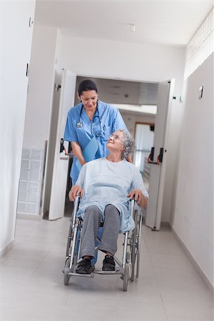 simsearch:400-07337135,k - Nurse pushing a patient in a wheelchair in hospital ward Stock Photo - Budget Royalty-Free & Subscription, Code: 400-06734414