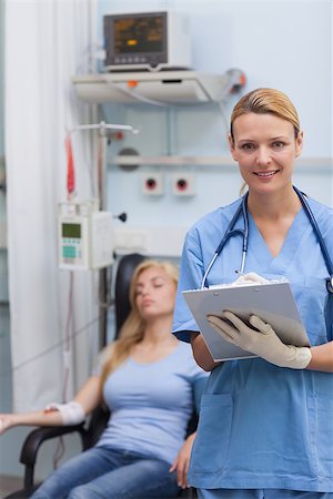 simsearch:400-06734658,k - Nurse holding a clipboard while looking at camera in hospital ward Stock Photo - Budget Royalty-Free & Subscription, Code: 400-06734562