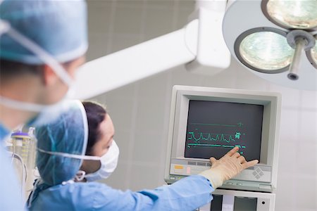 elettrocardiogramma - Doctor showing the ECG monitor in operating theater Fotografie stock - Microstock e Abbonamento, Codice: 400-06734609
