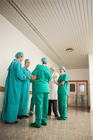 simsearch:400-06734621,k - Surgery team speaking to each other in hospital hallway Stock Photo - Budget Royalty-Free & Subscription, Code: 400-06734620