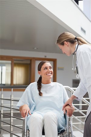 simsearch:6109-06195982,k - Smiling doctor touching a patient on a wheelchair in hospital corridor Fotografie stock - Microstock e Abbonamento, Codice: 400-06734677