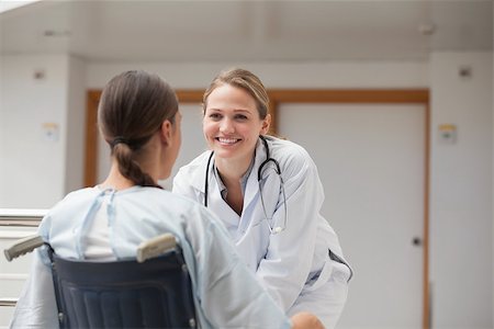 simsearch:6109-06195982,k - Smiling doctor in front of a patient on a wheelchair in hospital hallway Fotografie stock - Microstock e Abbonamento, Codice: 400-06734679