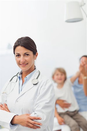 simsearch:400-06734647,k - Smiling doctor looking at camera with arms crossed in examination room Stock Photo - Budget Royalty-Free & Subscription, Code: 400-06734748