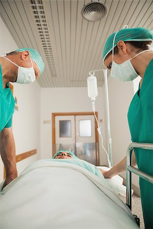 Surgeons looking at a patient asleep in hospital corridor Stock Photo - Budget Royalty-Free & Subscription, Code: 400-06734787