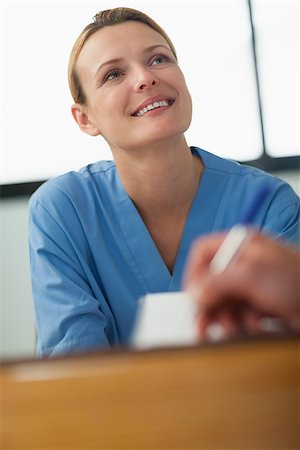 Nurse looking at someone who signing a paper in the hospital reception Stock Photo - Budget Royalty-Free & Subscription, Code: 400-06734810