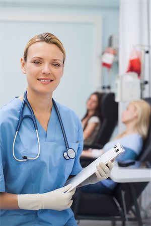 simsearch:400-06875952,k - Nurse looking at camera while holding a clipboard in hospital ward Stockbilder - Microstock & Abonnement, Bildnummer: 400-06734842