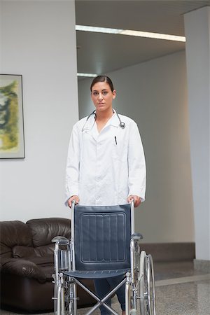 simsearch:6109-06195982,k - Doctor holding a wheelchair in hospital corridor Fotografie stock - Microstock e Abbonamento, Codice: 400-06735007