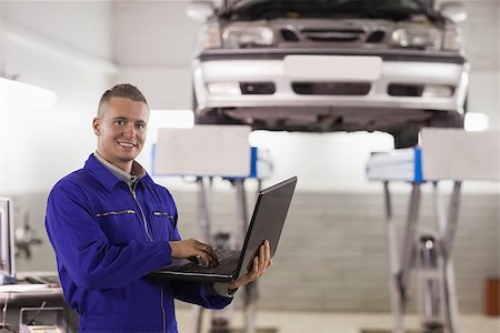 Mechanic typing on a laptop in a garage Stock Photo - Budget Royalty-Free & Subscription, Code: 400-06735165