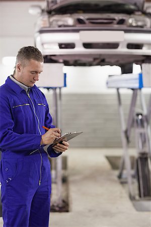 Concentrated mechanic holding a clipboard in a garage Stock Photo - Budget Royalty-Free & Subscription, Code: 400-06735162