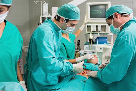 simsearch:400-06735487,k - Surgeons operating with surgical tools in an operating theatre Fotografie stock - Microstock e Abbonamento, Codice: 400-06735476