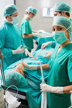 simsearch:400-06735487,k - Nurse looking at camera while holding an oxygen mask in an operating theatre Fotografie stock - Microstock e Abbonamento, Codice: 400-06735478