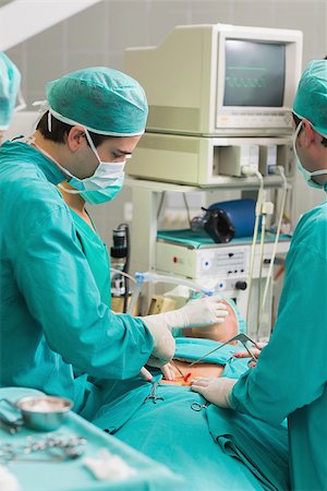 simsearch:400-06735487,k - Surgeons using surgical tools in an operating theatre Fotografie stock - Microstock e Abbonamento, Codice: 400-06735473