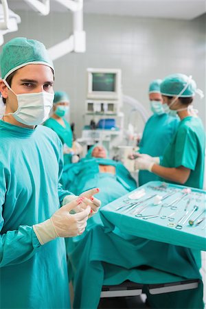 simsearch:400-06735487,k - Surgeon wearing gloves with blood next to a patient in an operating theatre Fotografie stock - Microstock e Abbonamento, Codice: 400-06735484