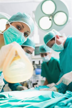 simsearch:400-06735487,k - Focus on a nurse holding an anesthesia mask in an operating theatre Fotografie stock - Microstock e Abbonamento, Codice: 400-06735486