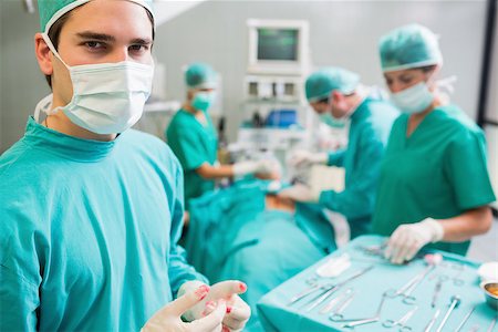 simsearch:400-06735487,k - Surgeon wearing bloody gloves while looking at camera in an operating theatre Fotografie stock - Microstock e Abbonamento, Codice: 400-06735483