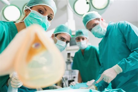 simsearch:400-06735487,k - Anesthesia mask holding by a nurse in an operating theatre Fotografie stock - Microstock e Abbonamento, Codice: 400-06735491