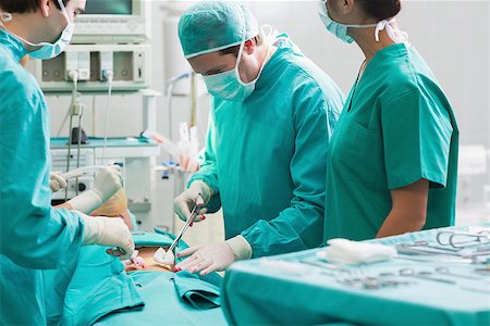 simsearch:400-06735487,k - Confident surgeon operating a patient in an operating theater in a hospital Fotografie stock - Microstock e Abbonamento, Codice: 400-06735547