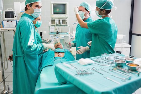 simsearch:400-06735487,k - Surgeon operating an uncounscious patient in an operating theater in a hospital Fotografie stock - Microstock e Abbonamento, Codice: 400-06735548