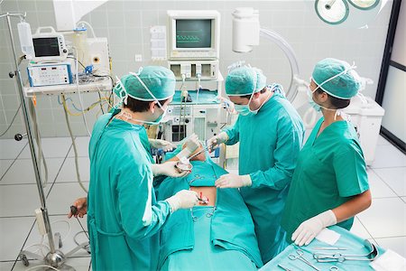 simsearch:400-06735487,k - Surgeons operating a patient in an operating theater in a hospital Fotografie stock - Microstock e Abbonamento, Codice: 400-06735554