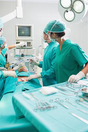 simsearch:400-06735487,k - Surgeons checking a monitor while operating in an operating theater Fotografie stock - Microstock e Abbonamento, Codice: 400-06735550