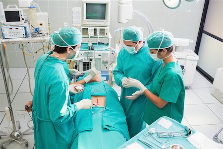 simsearch:400-06735487,k - High angle view of surgeon operating an uncounscious patient in an operating theater Fotografie stock - Microstock e Abbonamento, Codice: 400-06735551