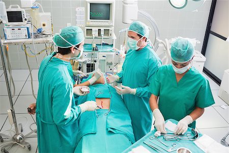 simsearch:400-06735487,k - Team of surgeons operating an uncounscious patient in an operating theater Fotografie stock - Microstock e Abbonamento, Codice: 400-06735552