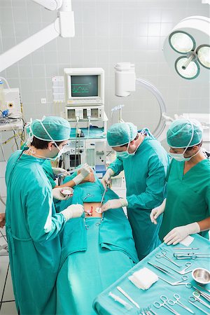 simsearch:400-06735487,k - Group of surgeon operating an unconscious patient in an operating theater in a hospital Fotografie stock - Microstock e Abbonamento, Codice: 400-06735553