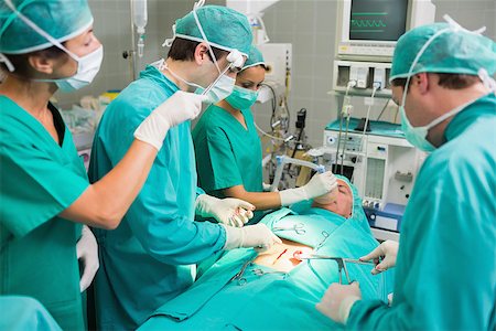 simsearch:400-06735487,k - Nurse drying the forehead of a surgeon in an operating theatre Fotografie stock - Microstock e Abbonamento, Codice: 400-06735565