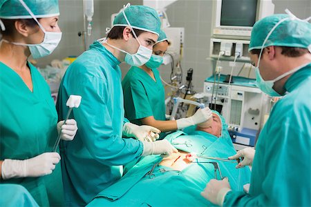 simsearch:400-06735487,k - Surgeons operating a patient belly in an operating theatre Fotografie stock - Microstock e Abbonamento, Codice: 400-06735566