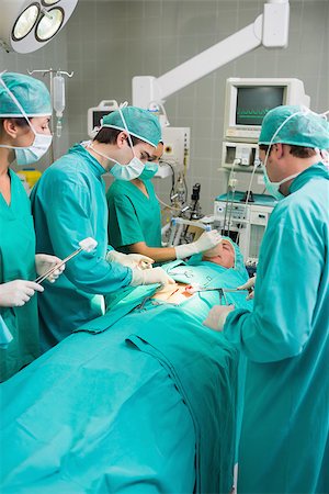 simsearch:400-06735487,k - Surgeons around the operating table in an operating theatre Fotografie stock - Microstock e Abbonamento, Codice: 400-06735567