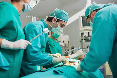 simsearch:400-06735487,k - Surgical team looking at a patient in an operating theatre Fotografie stock - Microstock e Abbonamento, Codice: 400-06735568