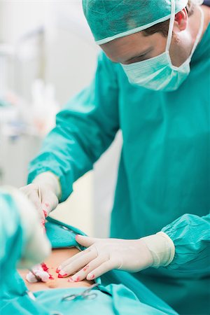 simsearch:400-06735487,k - Surgeon touching at patient belly in an operating theatre Fotografie stock - Microstock e Abbonamento, Codice: 400-06735560