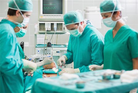simsearch:400-06735487,k - View of a surgical team operating a patient in an operating theatre Fotografie stock - Microstock e Abbonamento, Codice: 400-06735562