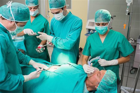 simsearch:400-06735487,k - Nurse giving a surgical tool to a surgeon in an operating theatre Fotografie stock - Microstock e Abbonamento, Codice: 400-06735576