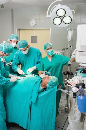 simsearch:400-06735487,k - Nurse adjusting a monitor in an operating theatre Fotografie stock - Microstock e Abbonamento, Codice: 400-06735577