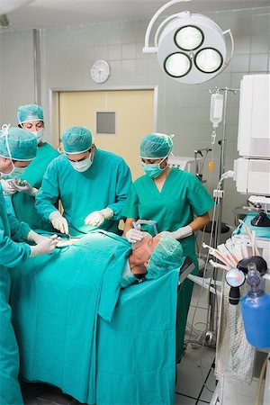 simsearch:400-06735487,k - Surgeons and nurses around a patient in an operating theatre Fotografie stock - Microstock e Abbonamento, Codice: 400-06735578