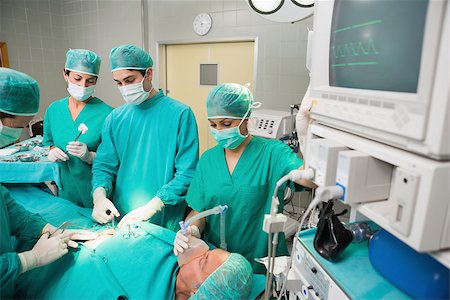 simsearch:400-06735487,k - Surgical team next to a monitor in an operating theatre Fotografie stock - Microstock e Abbonamento, Codice: 400-06735586