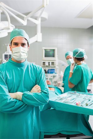 simsearch:400-06735487,k - Surgeon looking at camera with arms crossed in an operating theatre Fotografie stock - Microstock e Abbonamento, Codice: 400-06735588